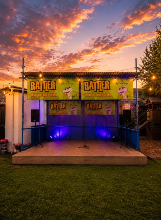 Outdoor live music stage at The Quintrell Inn in Quintrell Downs near Newquay, Cornwall, illuminated at sunset.