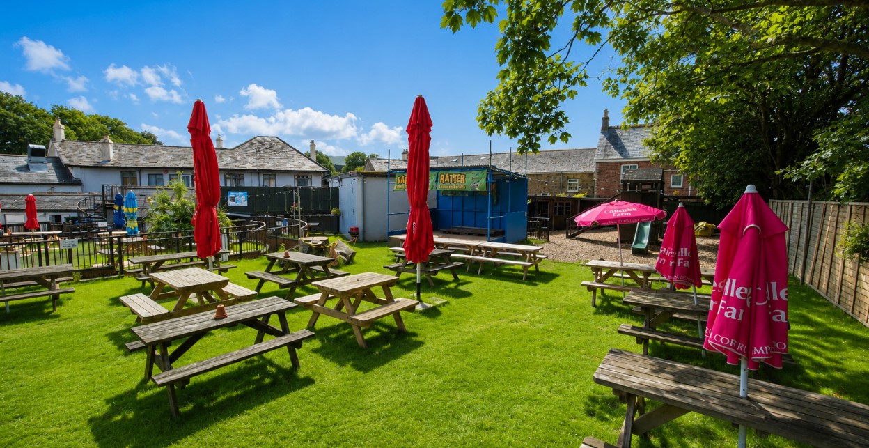 Beer garden at The Quintrell Inn near Newquay featuring outdoor seating, live music stage and family-friendly play area.